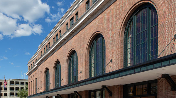 Brick rail station featuring large round arch windows and entryways.